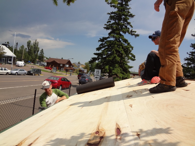 Rolling out the tar paper onto the roof