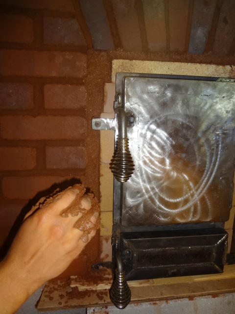 Filling in the area between the firebox and red brick with a mixture of vermiculite and clay