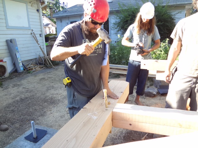 Assembling the first wall on site. Driving the pegs through the pre-drilled holes.